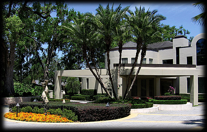 Picture of mansion with sculptures surrounded by landscaping.